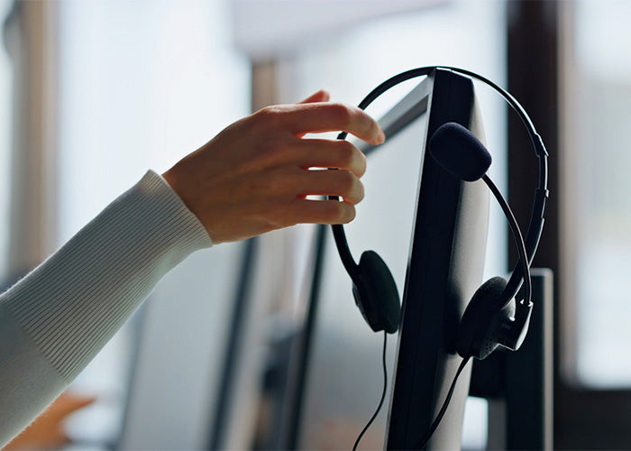Eine Mitarbeiterin, die aufgrund eines Anrufes zum Headset greift. 